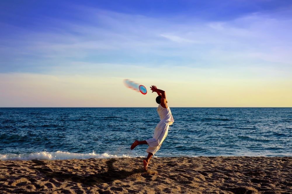 man catches frisbee in the beach