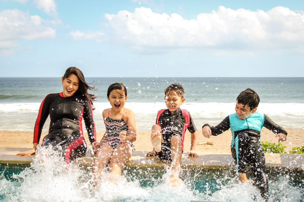 woman with three kids playing in the water in beach