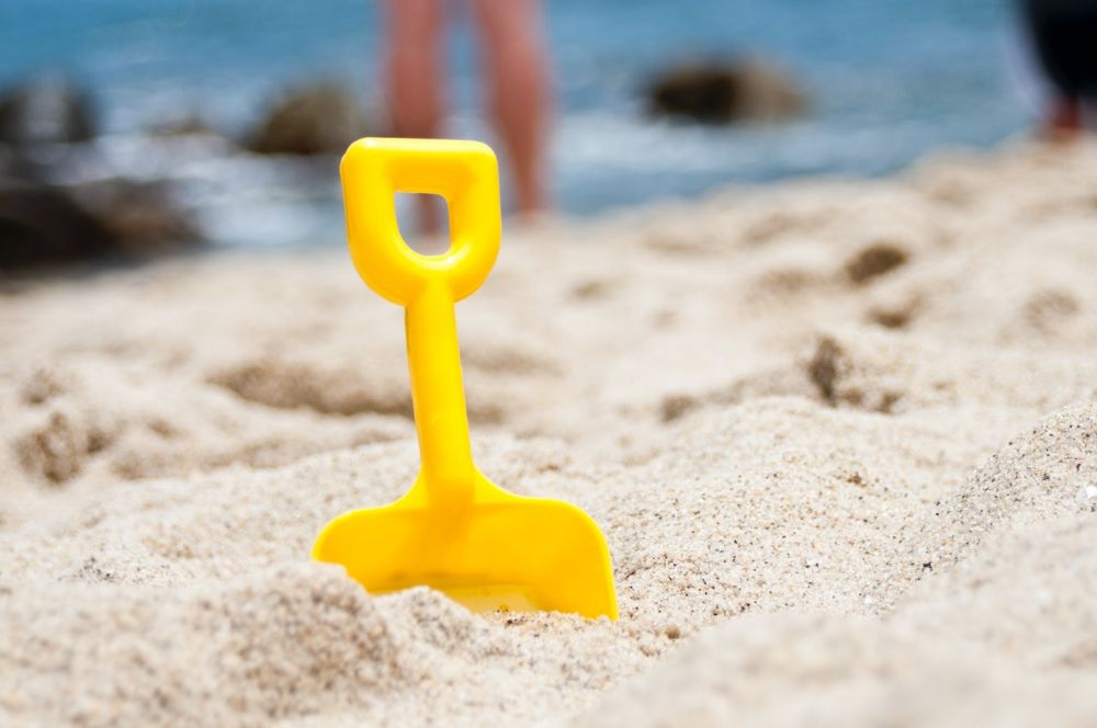 yellow toy shovel stuck in white sand