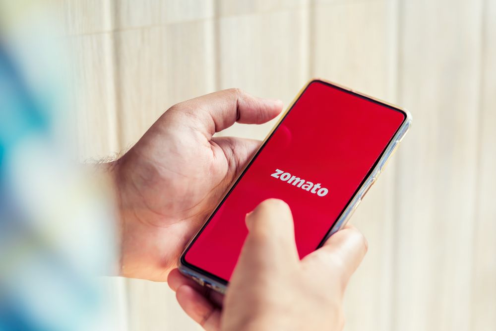 close up of person using phone with the Zomato logo on display